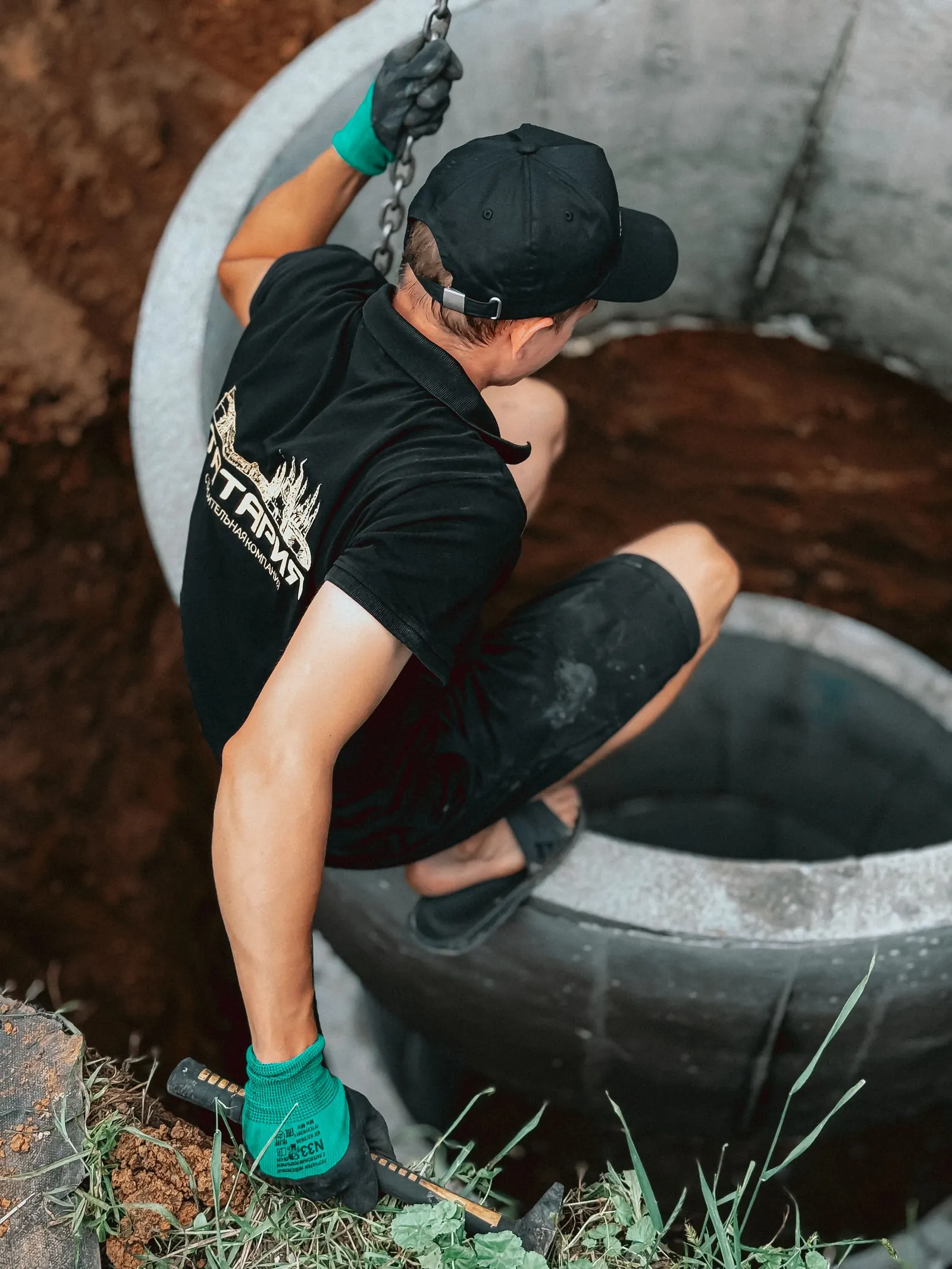 Worker handling a concrete septic access ring during field work